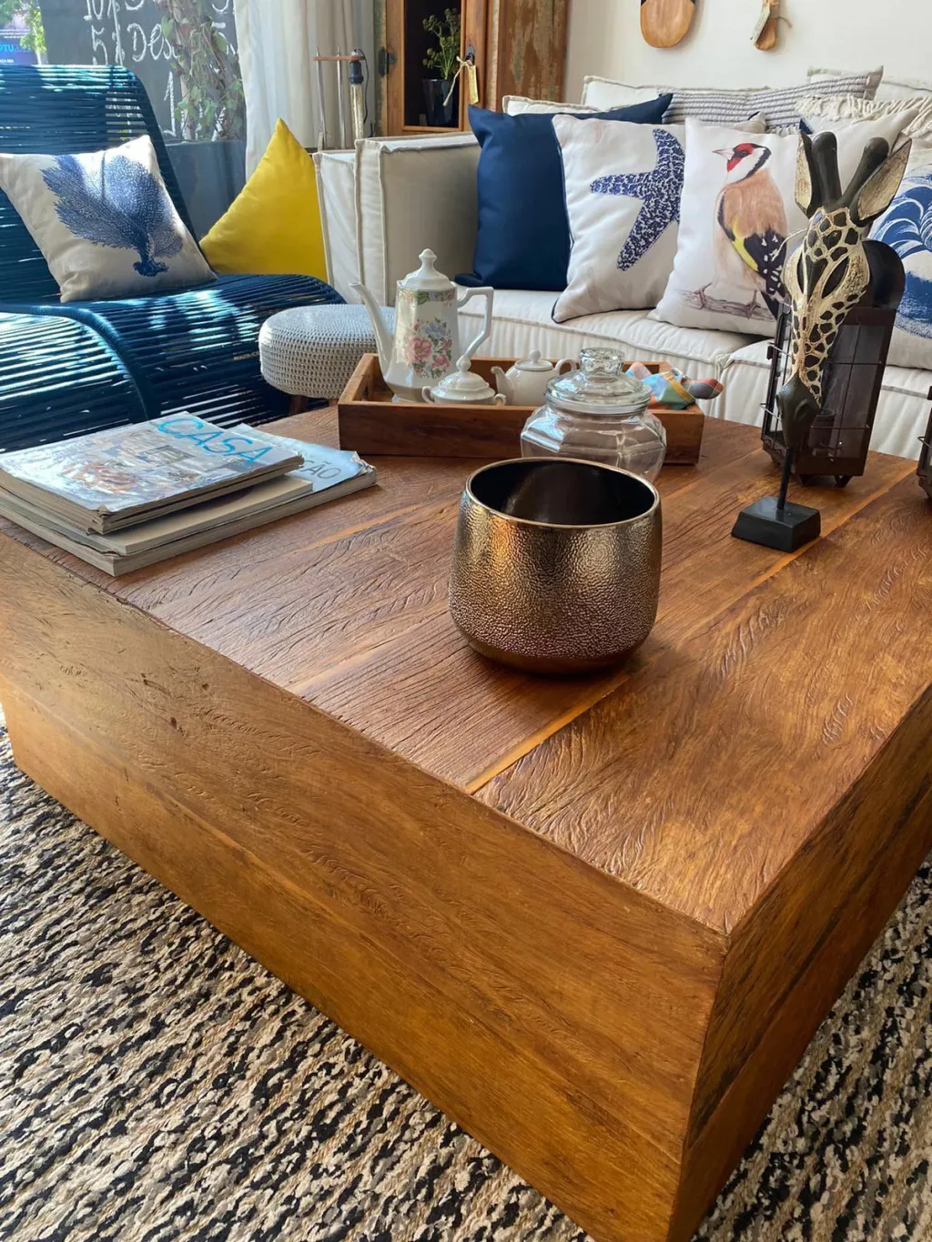 Mesa de centro em peroba de demolição com veios marcados, numa sala com sofá azul